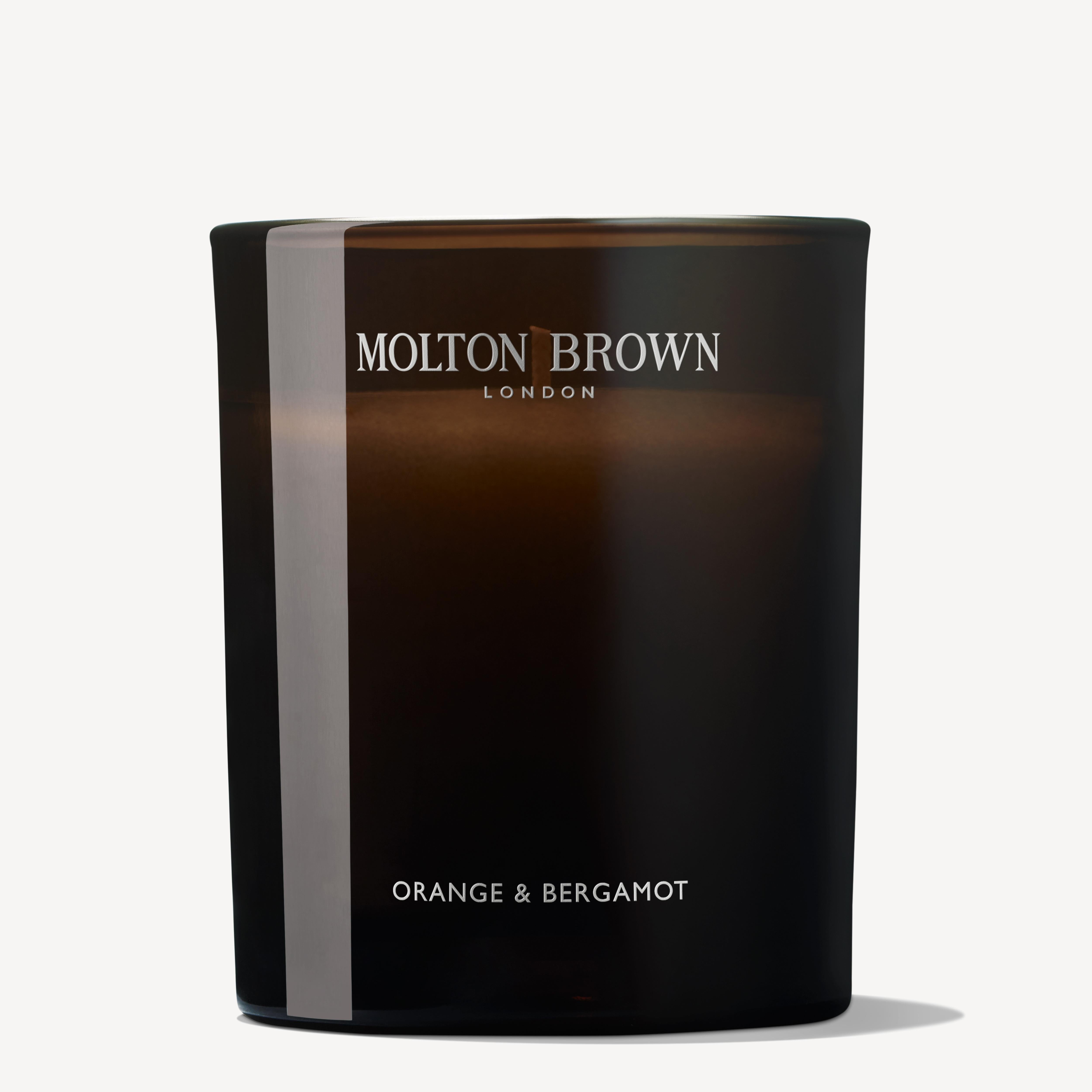 The Orange & Bergamot Signature Candle 190g by MoltonBrown Cyprus features a sleek, dark glass design, elegantly displaying "Orange & Bergamot" in simple lettering. Infused with a delicate orange mandarin fragrance, it offers a refined aromatic experience.