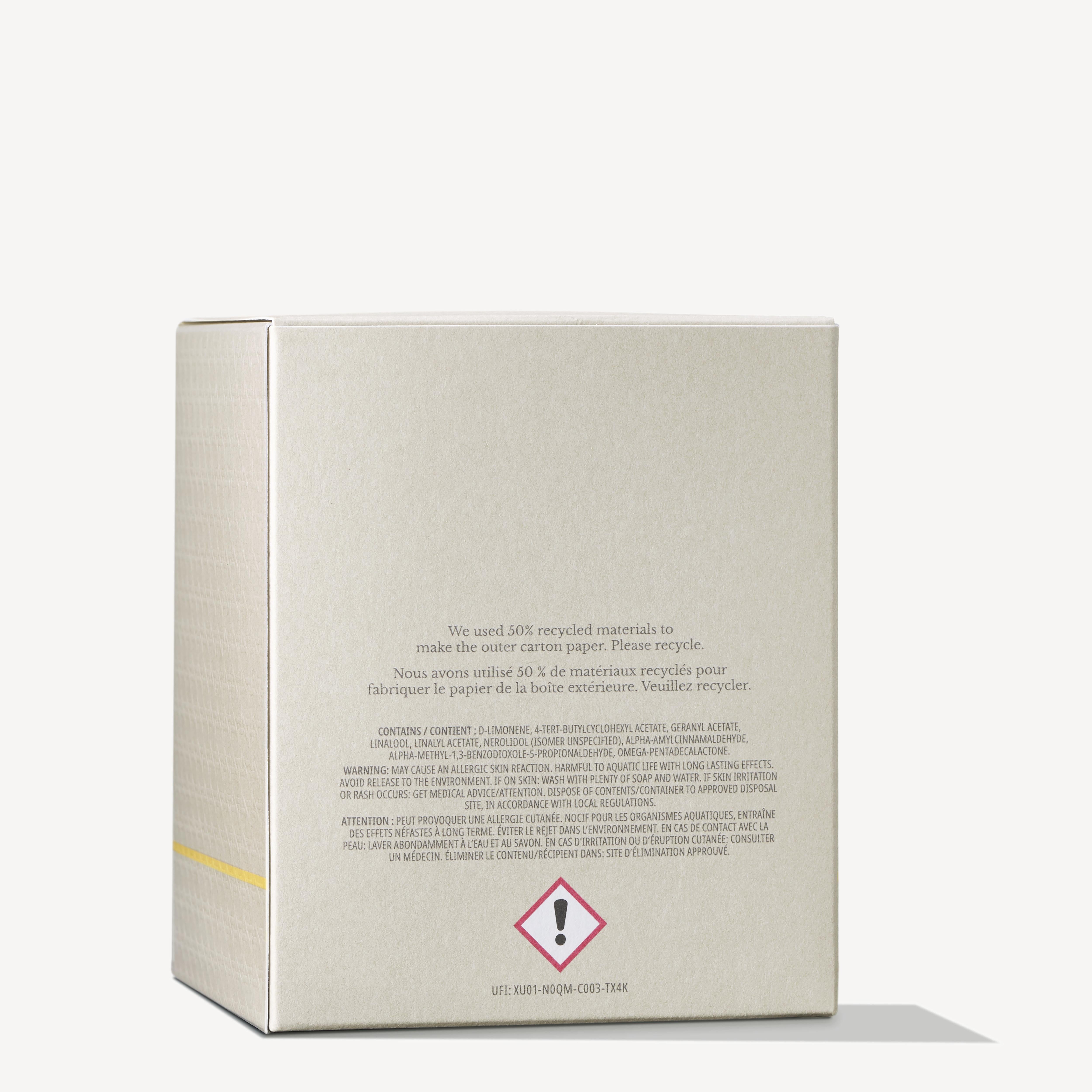 The image features a beige cardboard box displaying text and warning symbols on the back. It indicates that the packaging for the MoltonBrown Cyprus Orange & Bergamot Signature Candle 190g, which includes a single wick candle, is made from 50% recycled materials and is recyclable. A caution symbol is noticeable at the bottom.