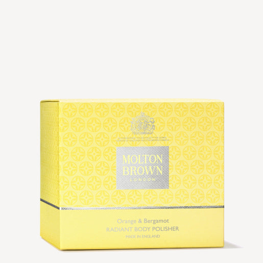 A yellow box of MoltonBrown Cyprus Orange & Bergamot Radiant Body Polisher 275g features a repeating geometric pattern and the brand logo. This exfoliating body scrub, made in England, delights with its invigorating citrus notes.