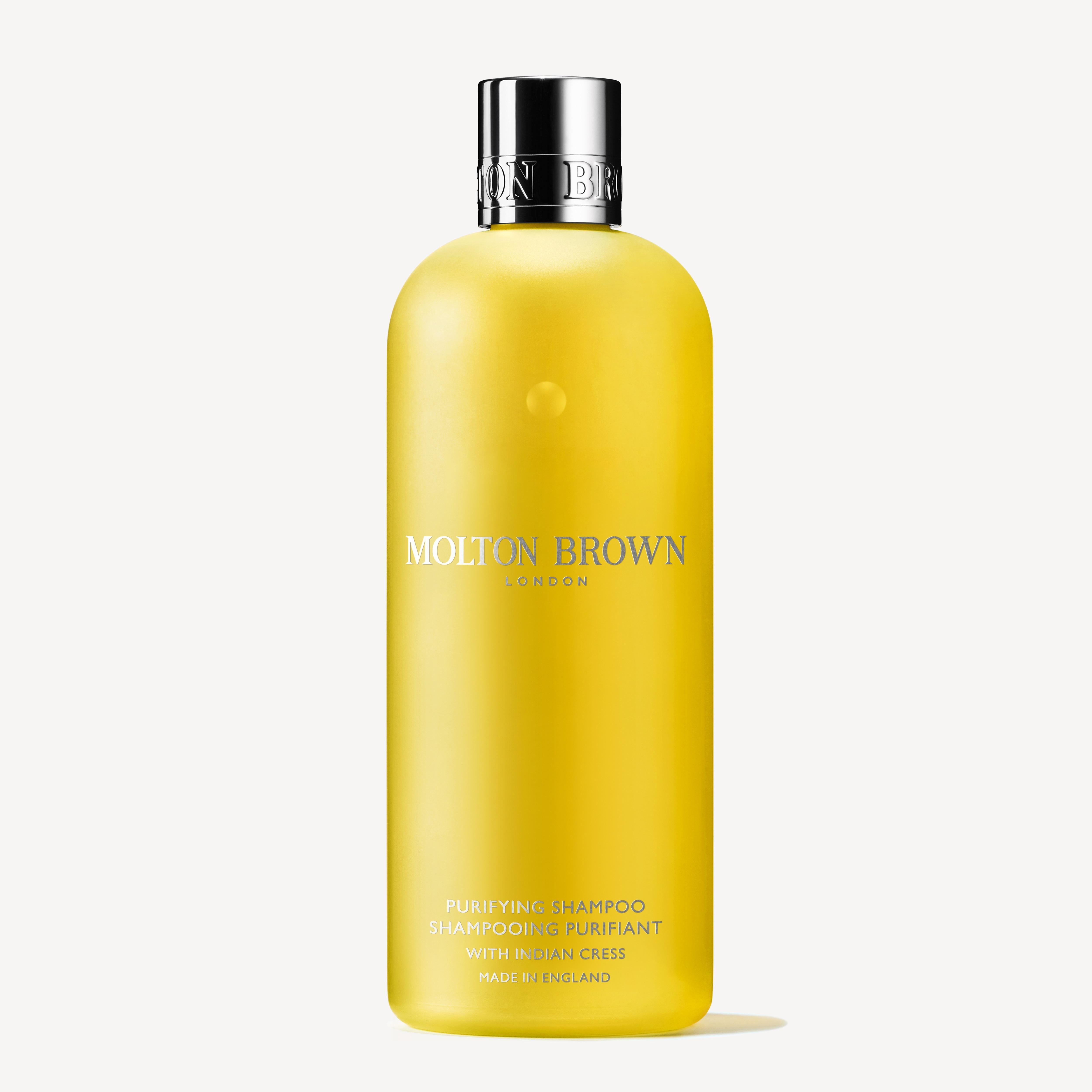 A yellow bottle of Purifying Shampoo With Indian Cress 300ml by MoltonBrown Cyprus, featuring a silver cap and white label text. The bottle stands elegantly against a plain white background, exuding a sense of purity and freshness.
