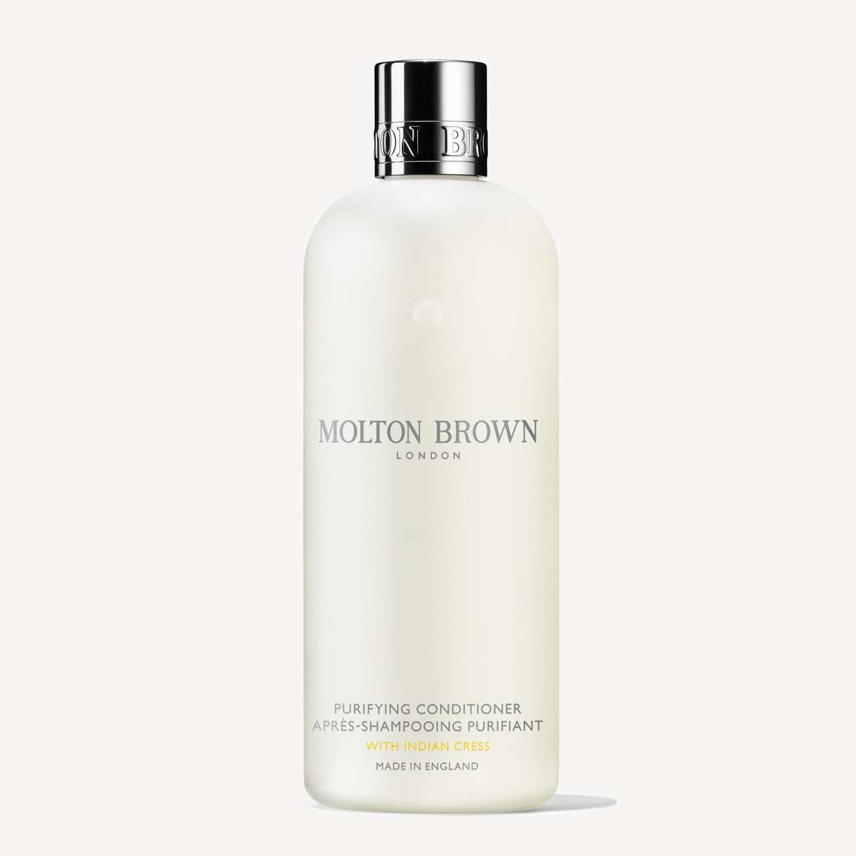 A white bottle of Molton Brown Cyprus Purifying Conditioner With Indian Cress 300ml is displayed. The text on the bottle features LONDON and Made in England in elegant fonts, with a simple, sleek design that exudes sophistication and is enhanced by subtle notes of honeysuckle.