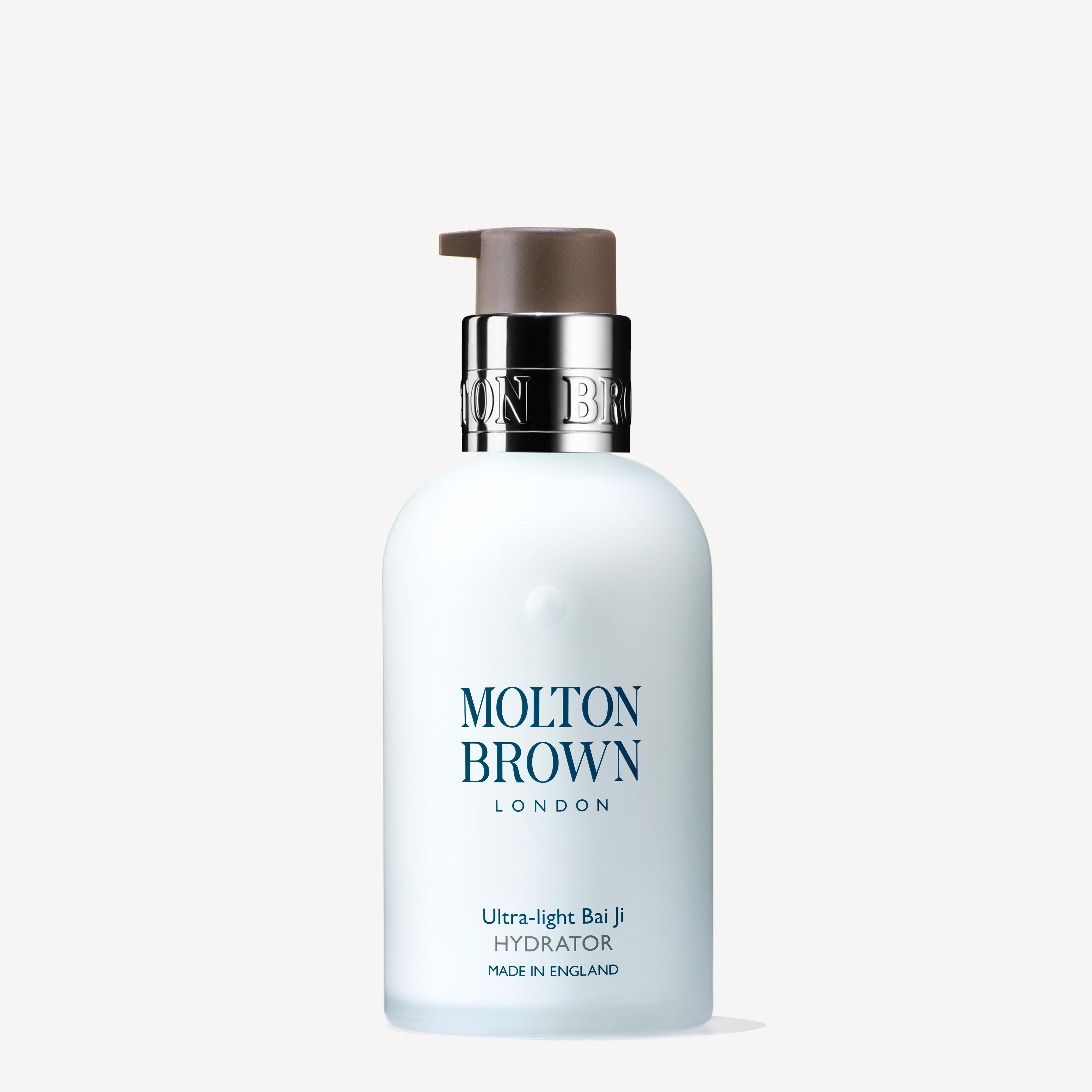 A white 100ml bottle of Molton Brown Cyprus Ultra-light Bai Ji Hydrator, enriched with bai ji extract, features a dark pump top against a light background. The label proudly reads Made in England.