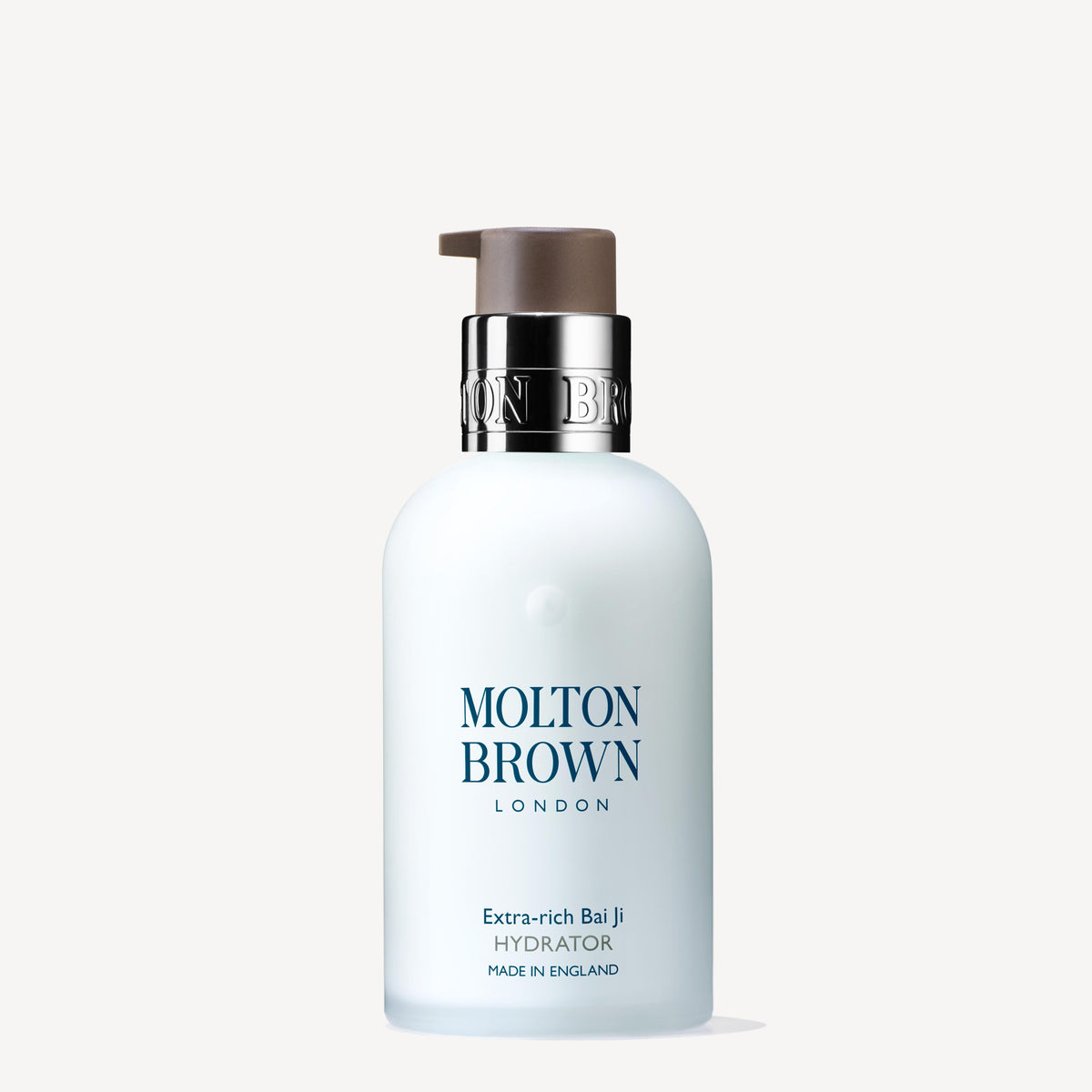 A white bottle of Molton Brown Cypruss Extra-rich Bai Ji Hydrator 100ml with a pump top features bai ji extract. The label states this luxurious moisturiser, enriched with macadamia seed oil for added nourishment, is made in England.