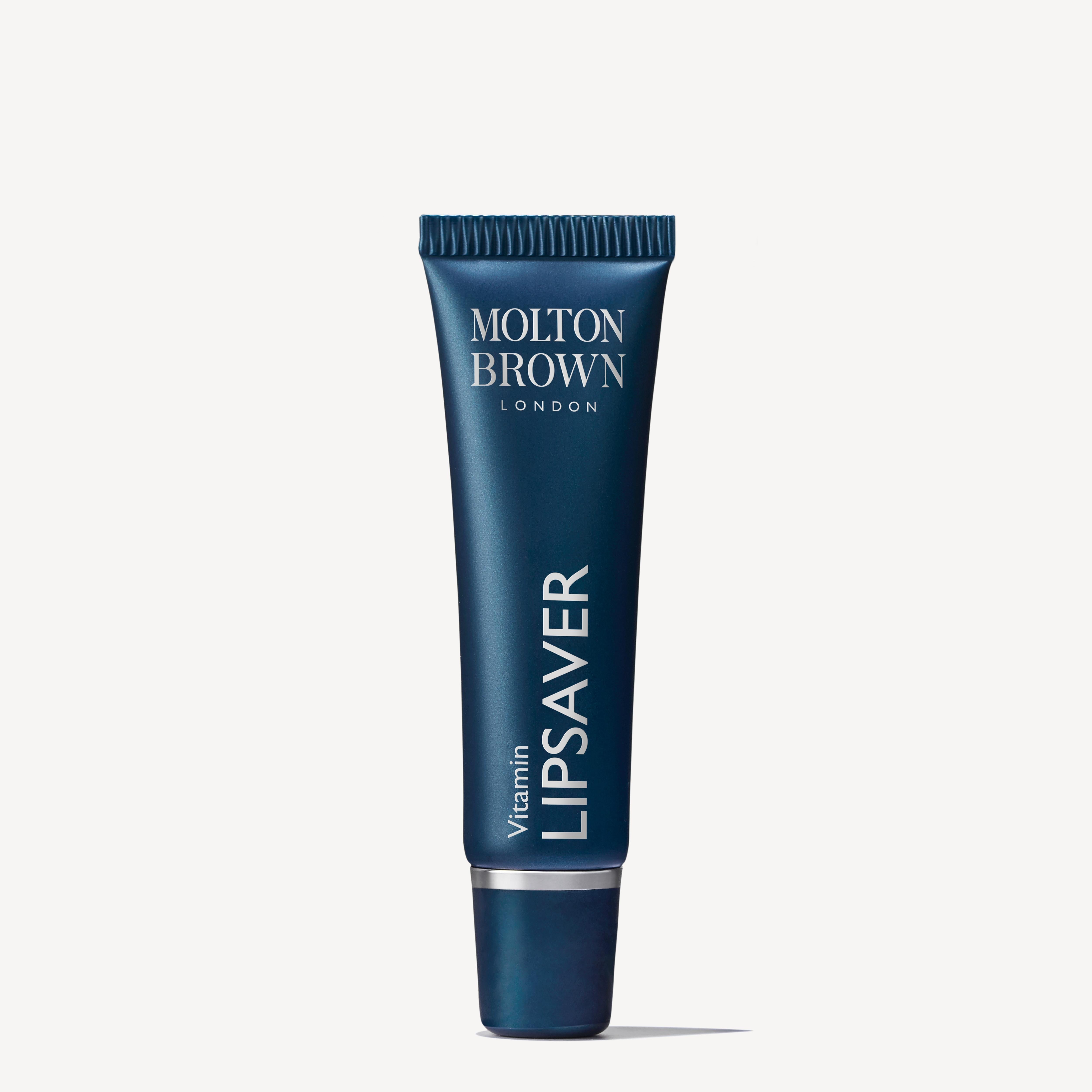 A dark blue tube of Molton Brown Cyprus Vitamin Lipsaver 10ml lip balm with a screw cap, labeled in white text, is enriched with vitamin E and cocoa butter to moisturize and protect lips.