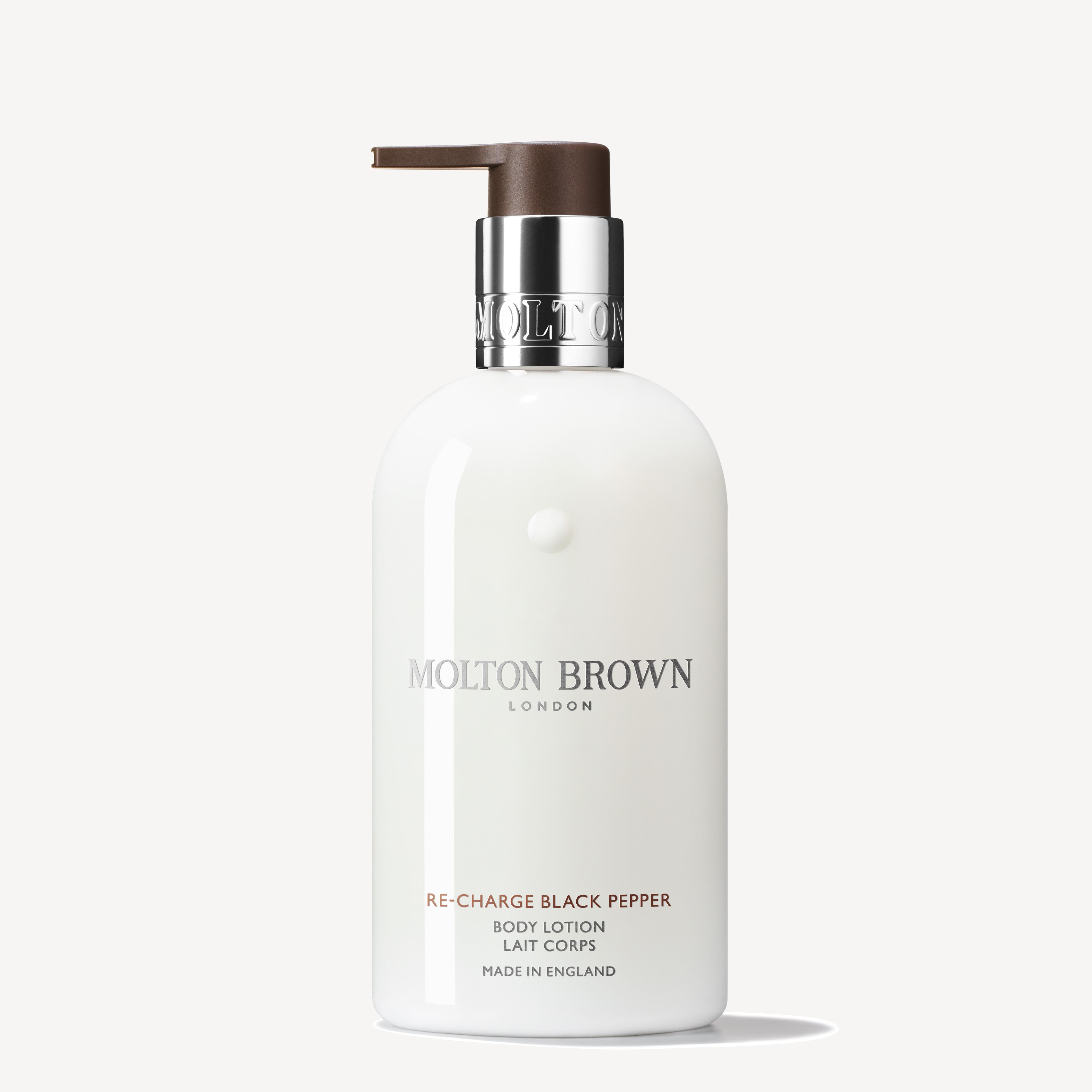 A 300ml bottle of Re-charge Black Pepper Body Lotion by MoltonBrown Cyprus, enriched with vetiver for an invigorating aroma. It includes a pump dispenser and a sleek design, prominently featuring the brand and product details on the label, crafted in England against a plain background.