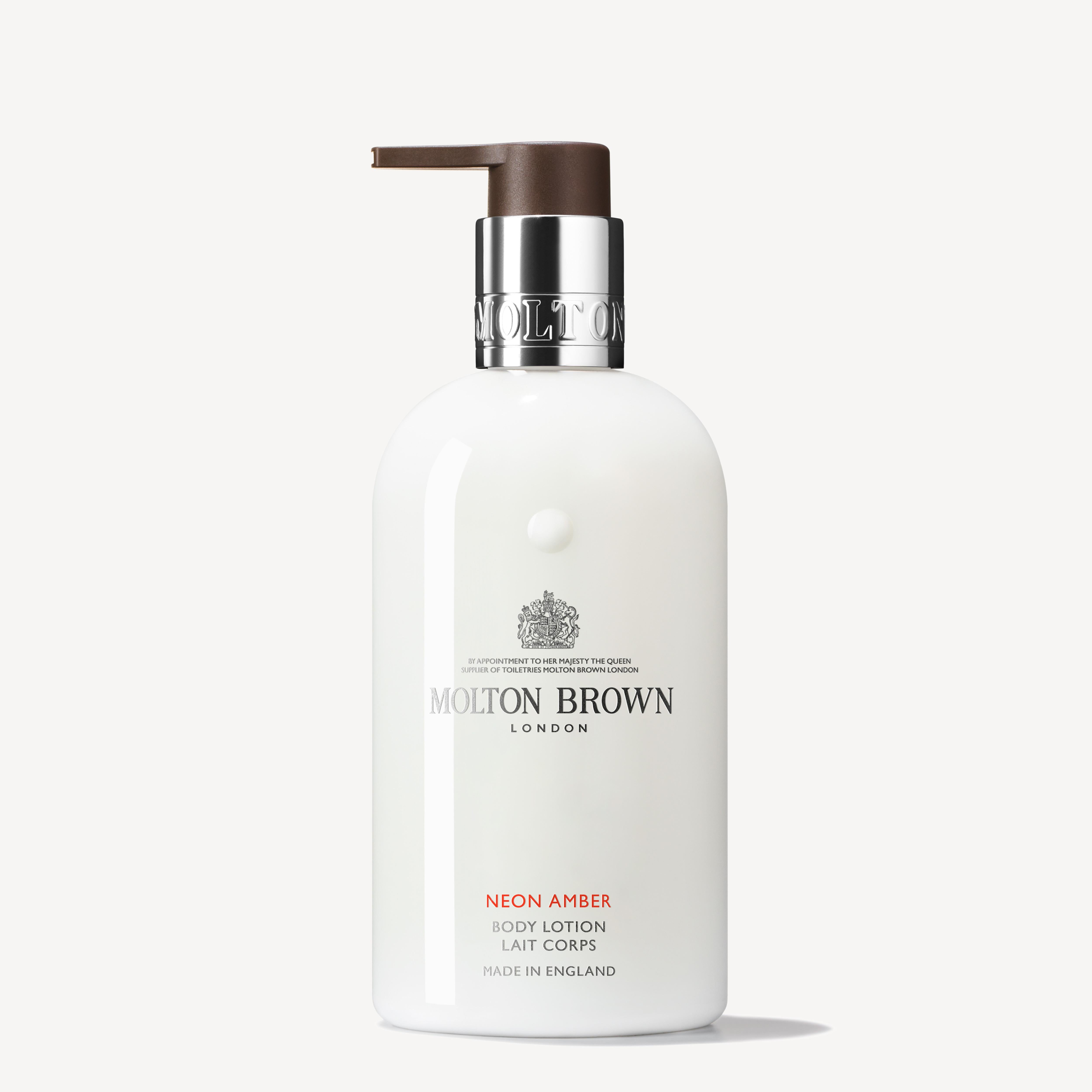 A 300ml bottle of MoltonBrown Cyprus Neon Amber Body Lotion with a pump dispenser. The packaging features a white label with silver and brown accents, showcasing the brand logo and product details, highlighting its infusion of mandarin oil and proudly stating it's made in England.