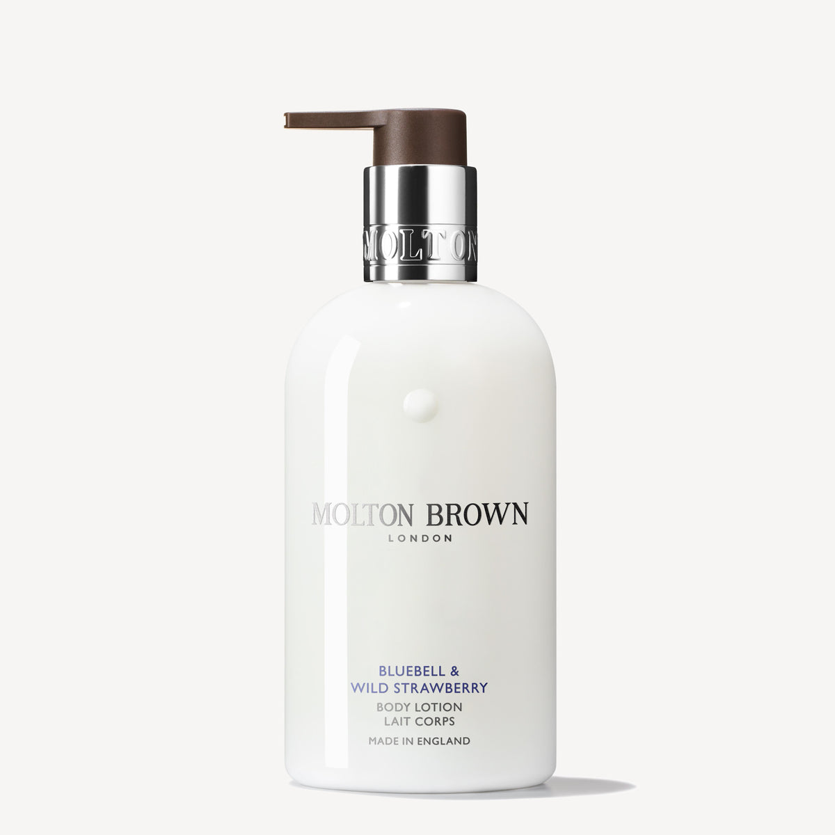 A white bottle of Bluebell & Wild Strawberry Body Lotion by MoltonBrown Cyprus, featuring a brown pump dispenser, exudes a floral-fruity scent. The brand logo and product details shimmer in silver and purple against the white background.