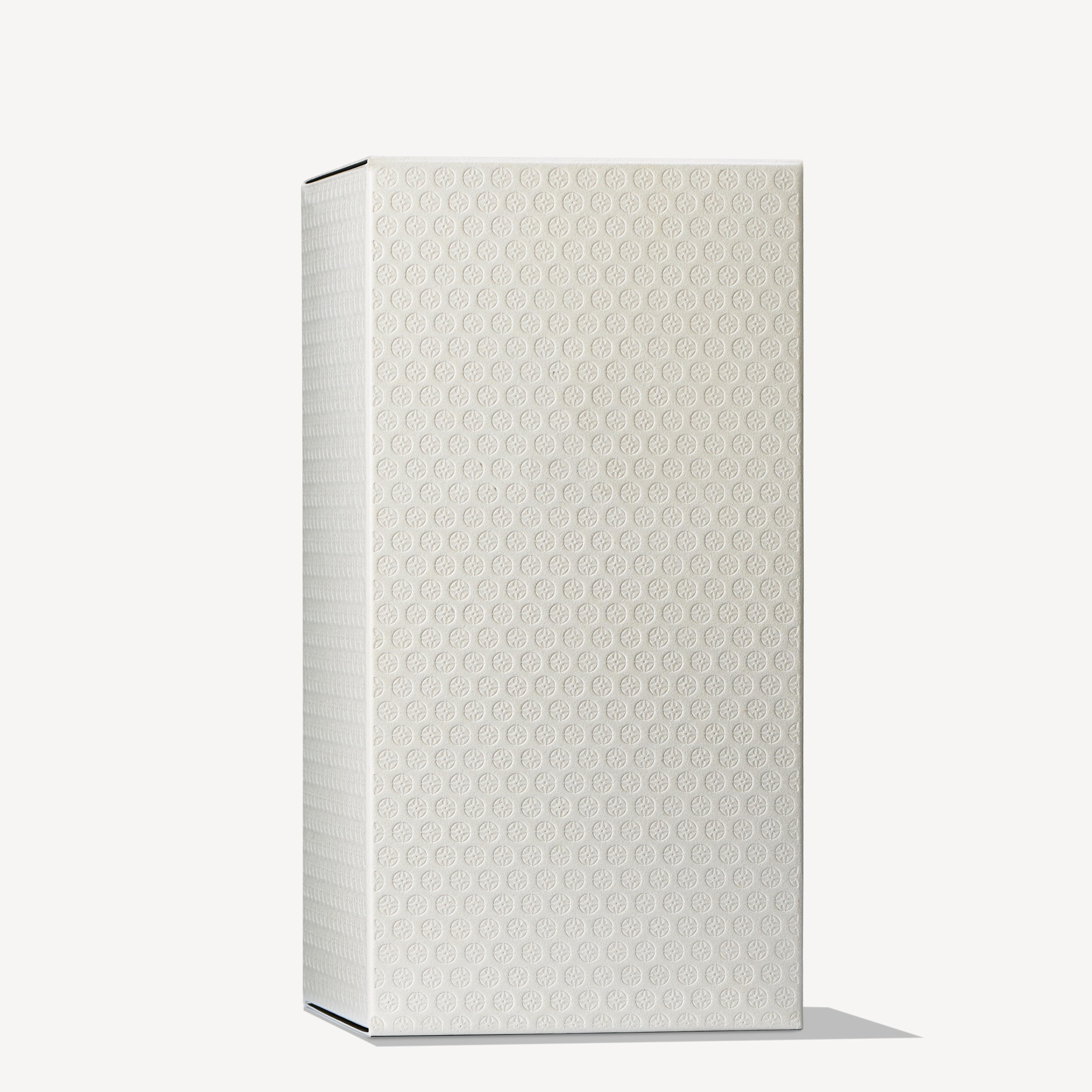 A tall, rectangular white box adorned with a delicate small circular pattern casts a gentle shadow on the light background—a design evocative of the Mesmerising Oudh Accord & Gold Eau de Toilette 100ml by MoltonBrown Cyprus packaging.
