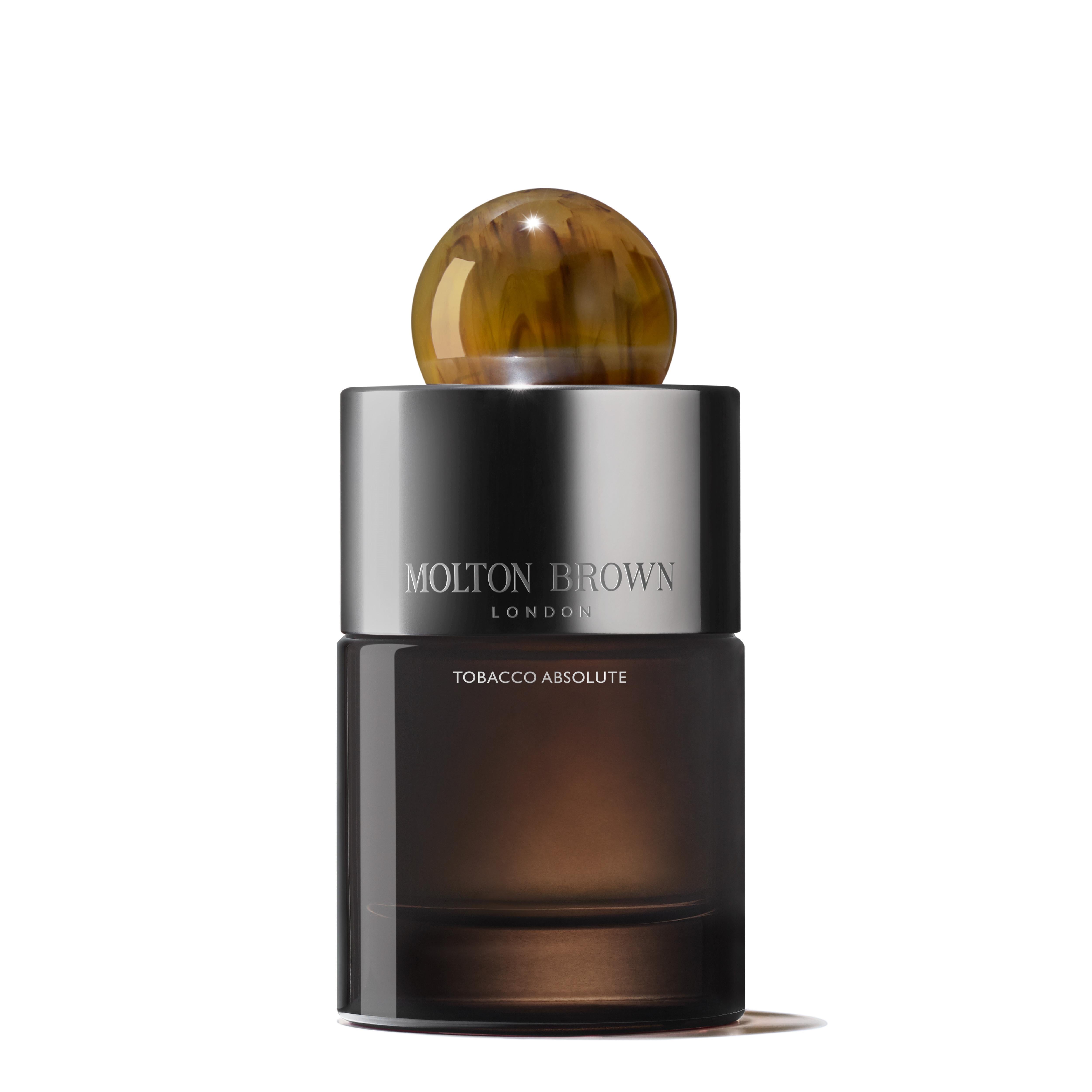 A stylish bottle of MoltonBrown Cyprus's Tobacco Absolute Eau de Parfum 100ml features a transparent container that reveals a rich, smoky tobacco hue and is finished with a marbled brown cap. The label is adorned with elegant silver lettering.