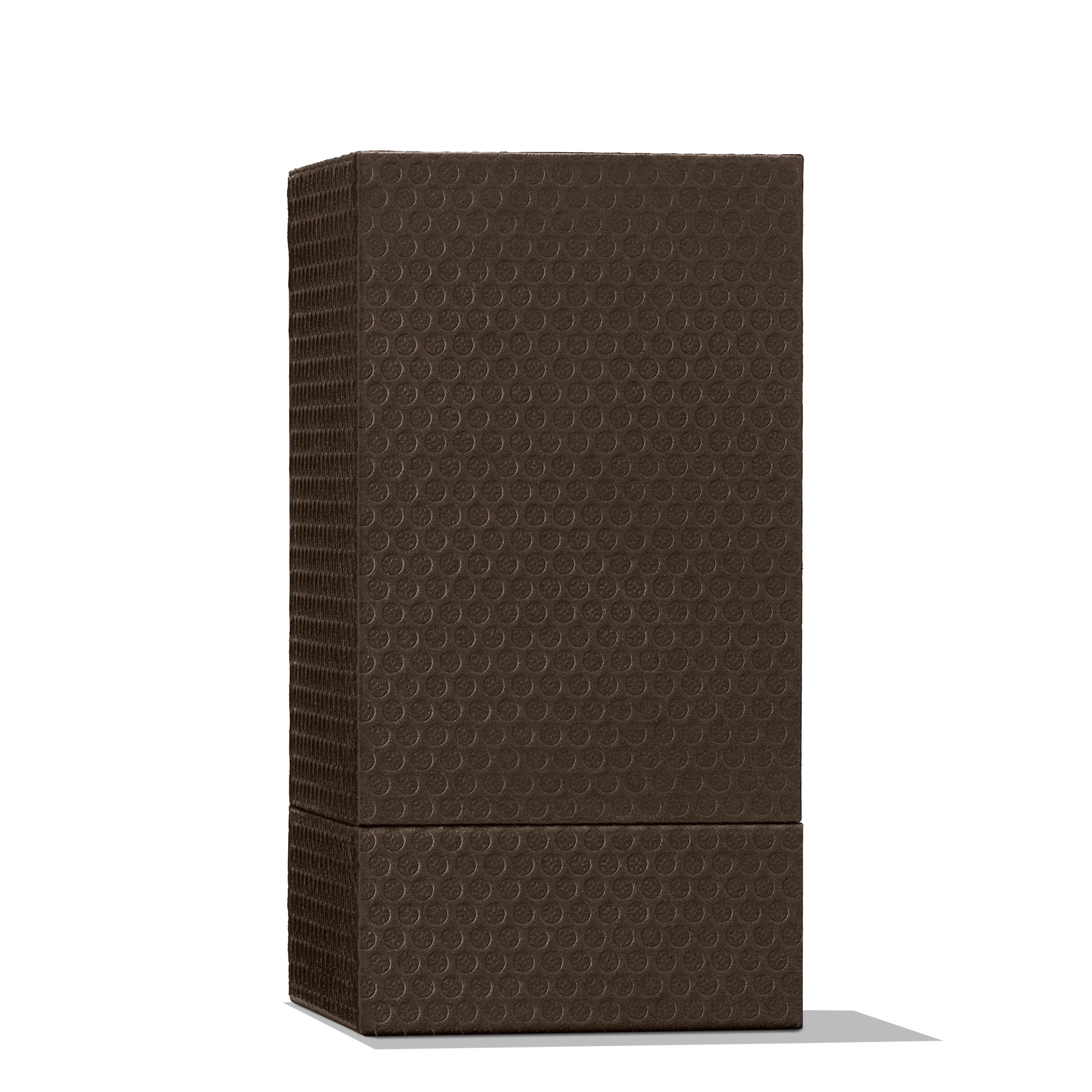 A dark chocolate bar stands upright against a white backdrop, its surface textured with a pattern of small, raised circles. This delightful treat offers an exotic escape akin to the allure of Molton Brown Cyprus's Heavenly Gingerlily Eau de Parfum 100ml, where each bite captivates like its fragrant essence.