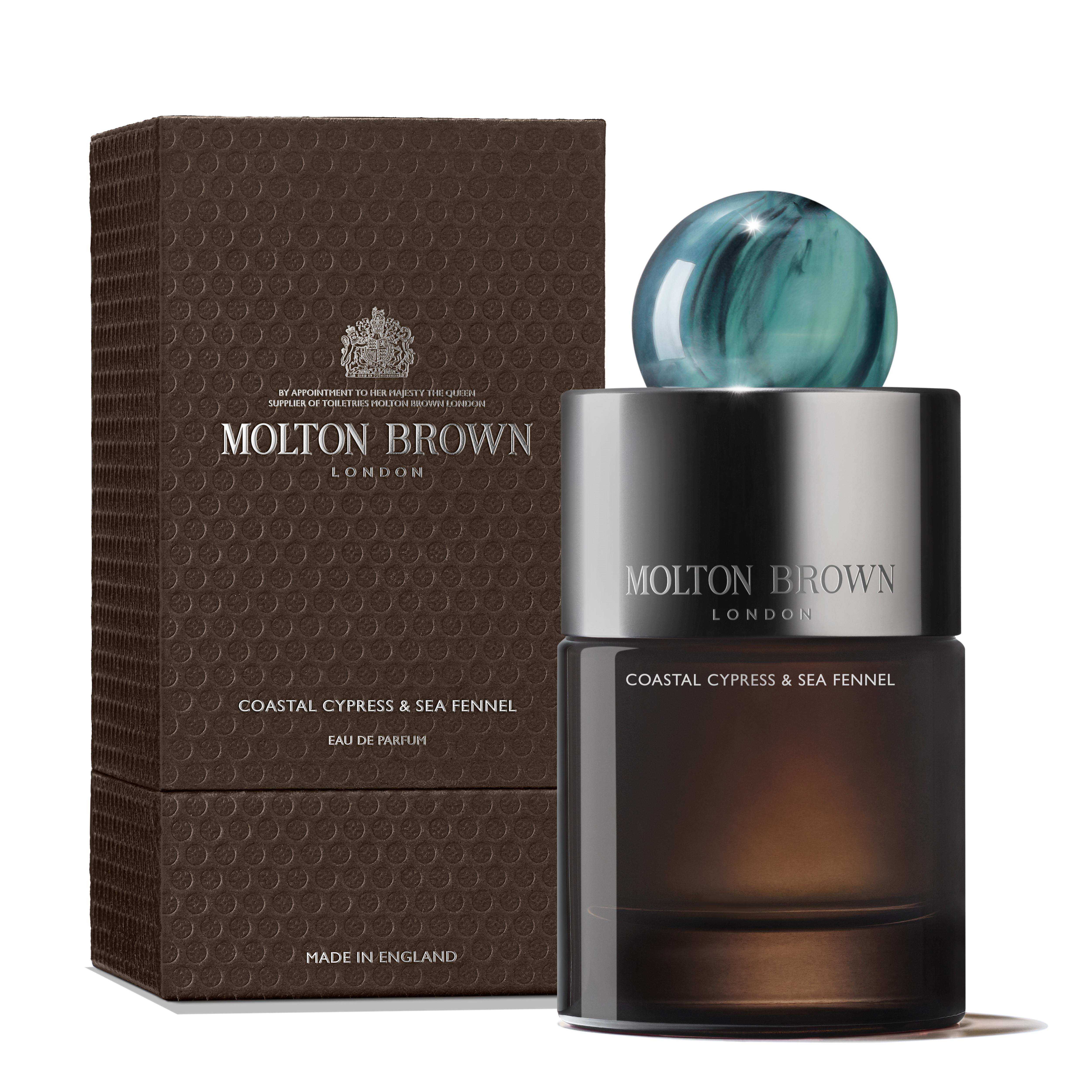A bottle of MoltonBrown Cyprus Coastal Cypress & Sea Fennel Eau de Parfum 100ml, showcasing an ocean-inspired design with a teal spherical cap, is placed next to its textured brown box. The packaging features elegant, minimalist text and branding.