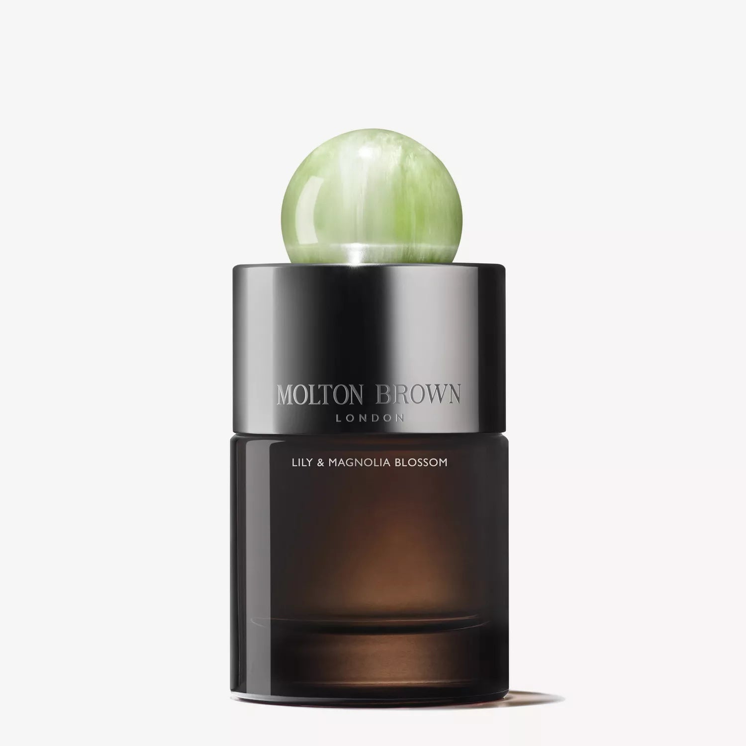 Molton Brown Cyprus presents the Lily & Magnolia Blossom Eau de Parfum 100ml, a floral fragrance in an elegant cylindrical bottle with a dark gradient, topped by a shiny, marble-like light green round cap.