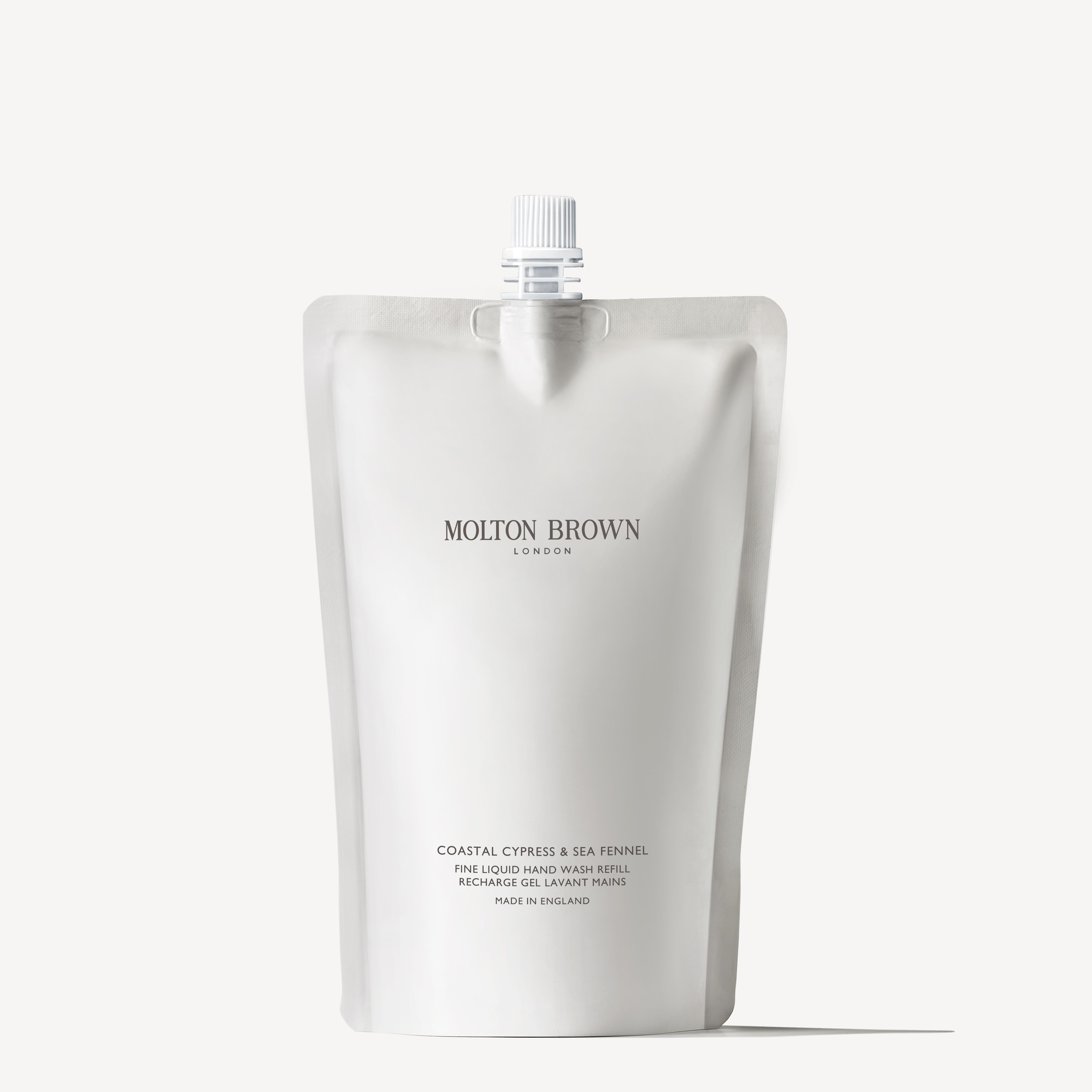 A white pouch featuring a nozzle and labeled MoltonBrown Cyprus contains a sustainable refill of Coastal Cypress & Sea Fennel Fine Liquid Hand Wash. The minimalist packaging offers a marine scent adventure, with "Made in England" prominently displayed at the bottom.