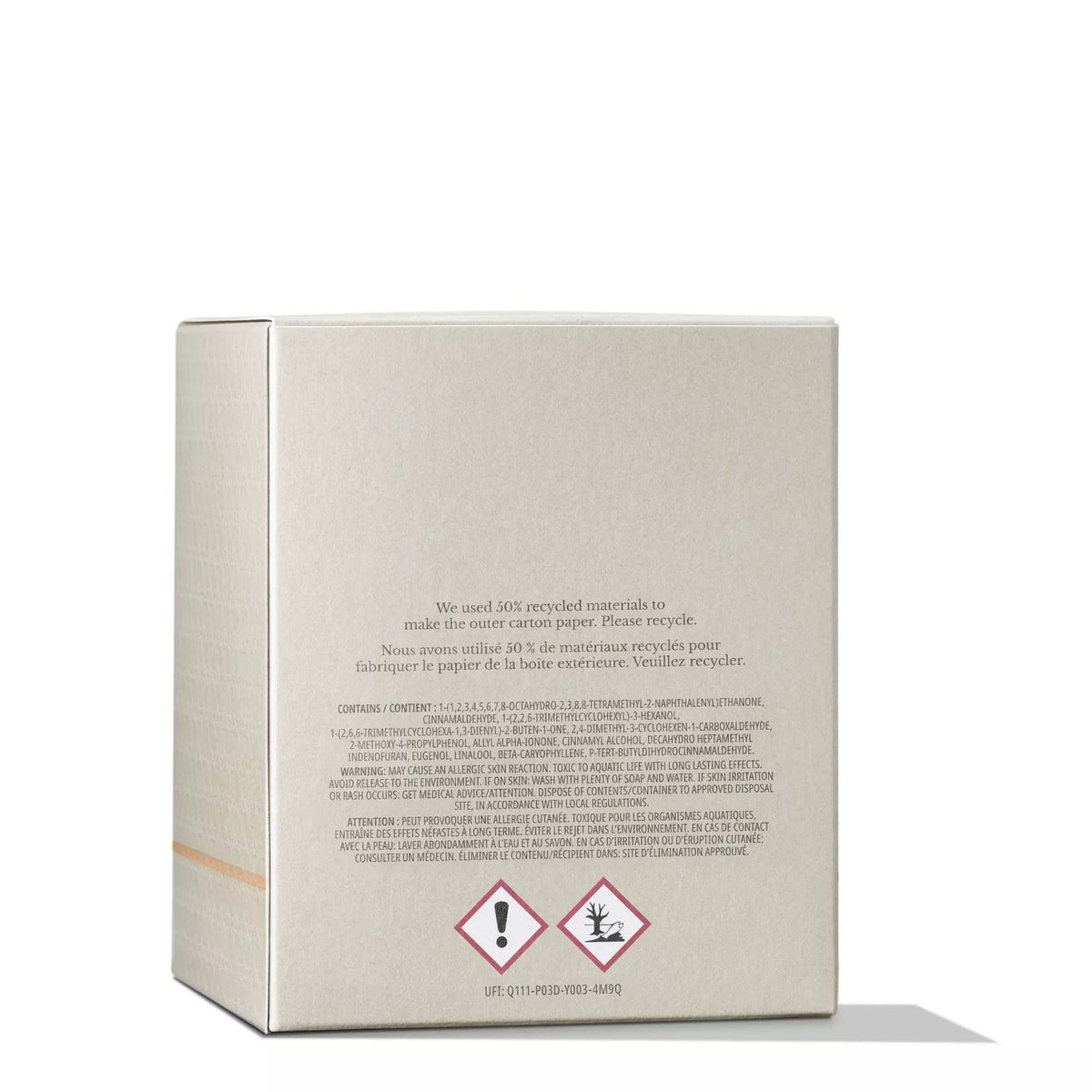 A beige cardboard box reveals the opulent scent of Molton Brown Cyprus Mesmerising Oudh Accord & Gold Signature Candle 190g. Printed text in English and French about recycled materials features below two warnings: an exclamation mark and a dead tree, all set against a white background.