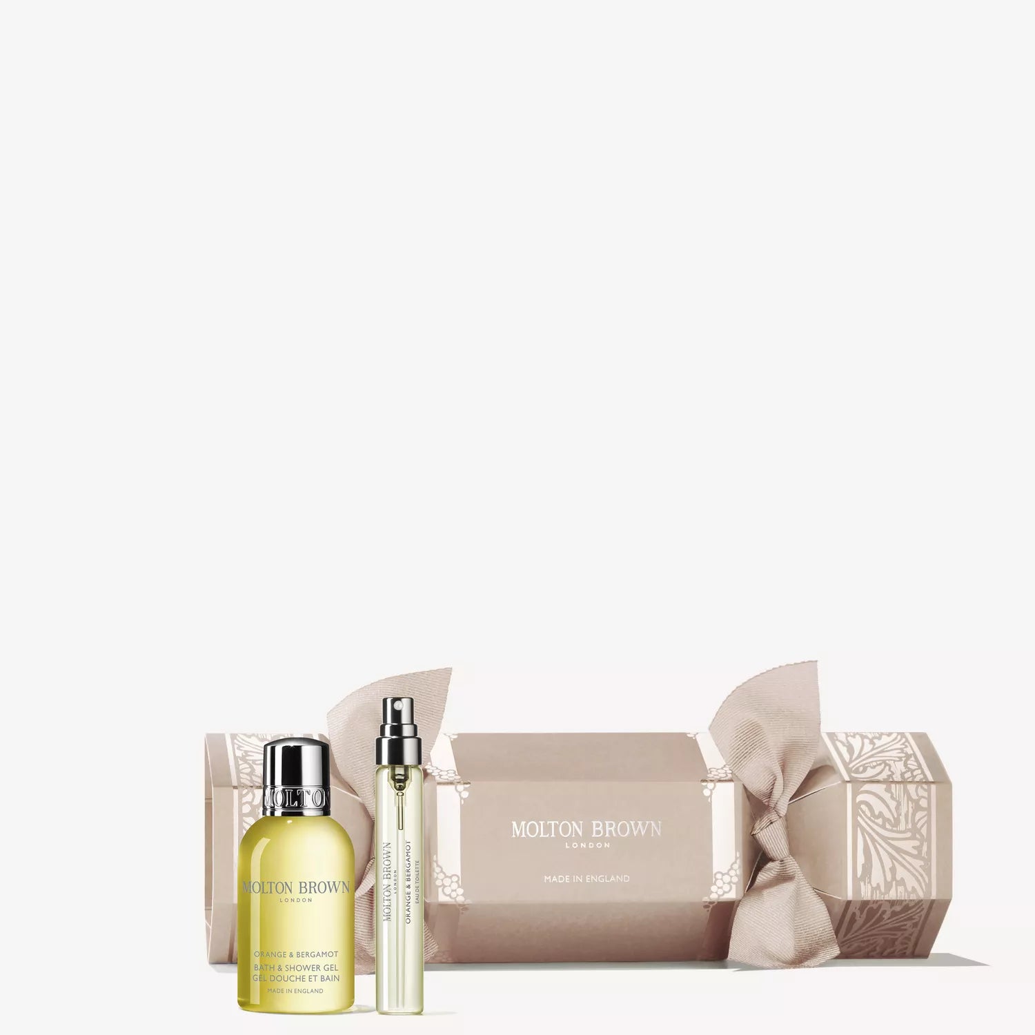 A MoltonBrown Cyprus Orange & Bergamot Christmas Cracker with ornate white detailing is displayed, accompanied by a small yellow citrus-scented bottle and a slender spray, all set neatly on a white background.