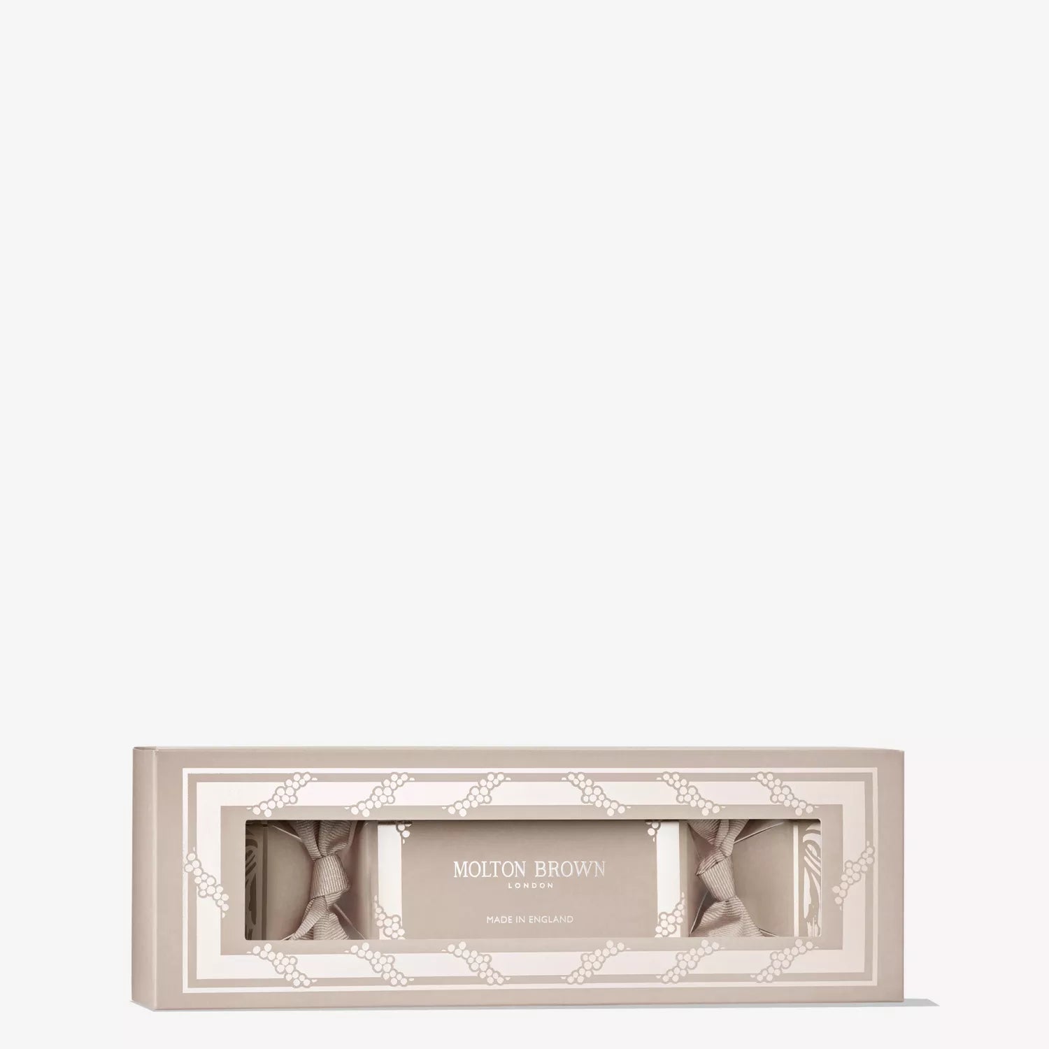 The Orange & Bergamot Christmas Cracker by MoltonBrown Cyprus is a beige rectangular gift box with a clear window, revealing three wrapped bath or body treats inside. Its elegant packaging and citrus scent make it a perfect Christmas table gift.