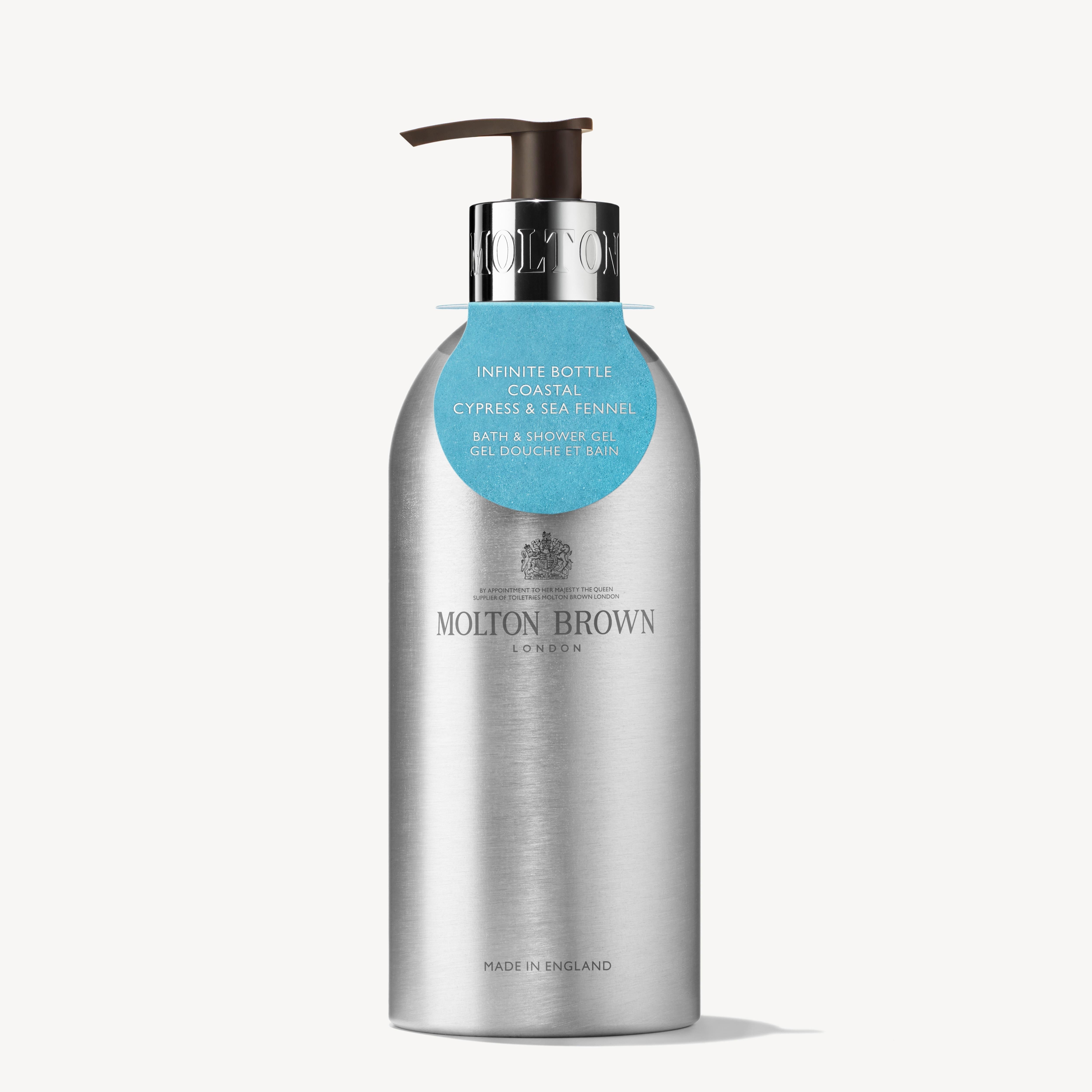 A 400ml silver recycled aluminum MoltonBrown Cyprus bottle of bath and shower gel, featuring a black pump and adorned with a blue tag at the neck. The label displays "Coastal Cypress & Sea Fennel," and "Made in England" is printed at the bottom, making it an ideal choice for a sustainable bathing routine.